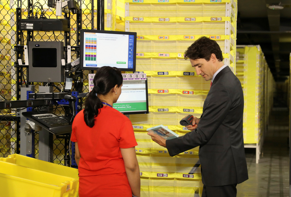 Canada's Prime Minister Justin Trudeau scans merchandise with an employee during a tour of the Amazon Fulfillment Centre in Brampton, Ontario, Canada October 20, 2016. Trudeau has set a deadline of Monday to decide whether to fly to Brussels, according to