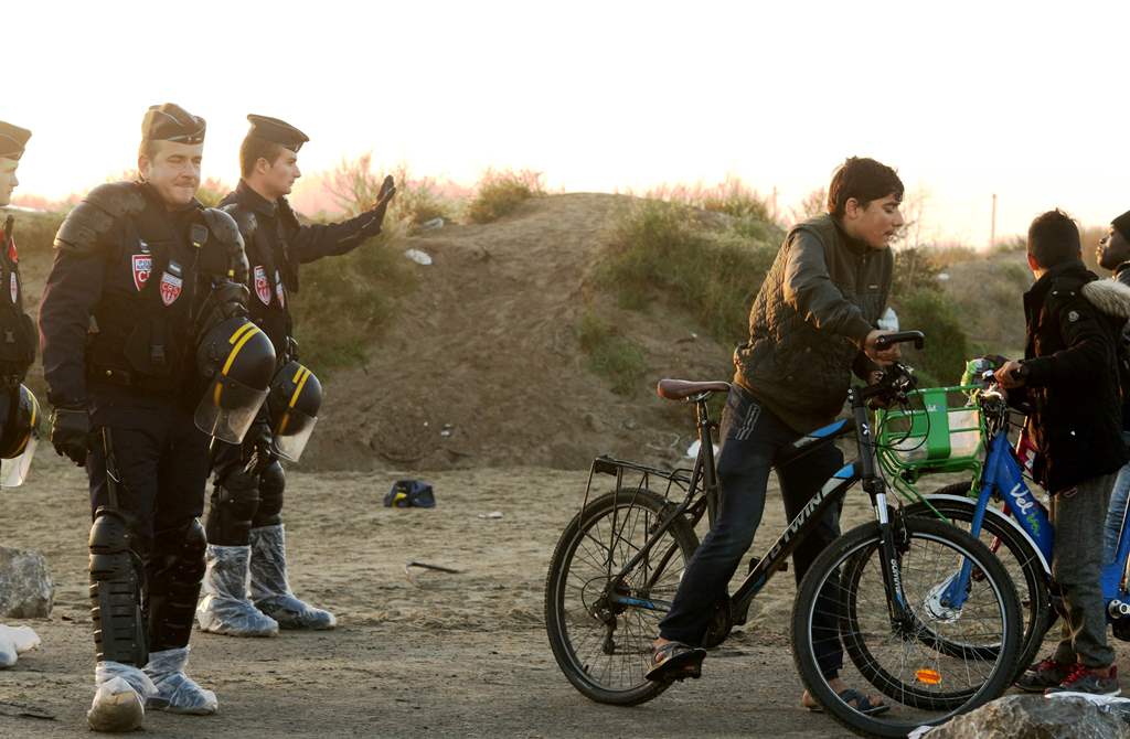 French policemen stand guard a track as children ride their bicycles in the 