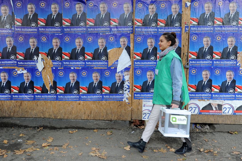 An official walks with a ballot box along election posters during the second round of parliamentary elections in Tbilisi on October 30, 2016. AFP / Vano Shlamov