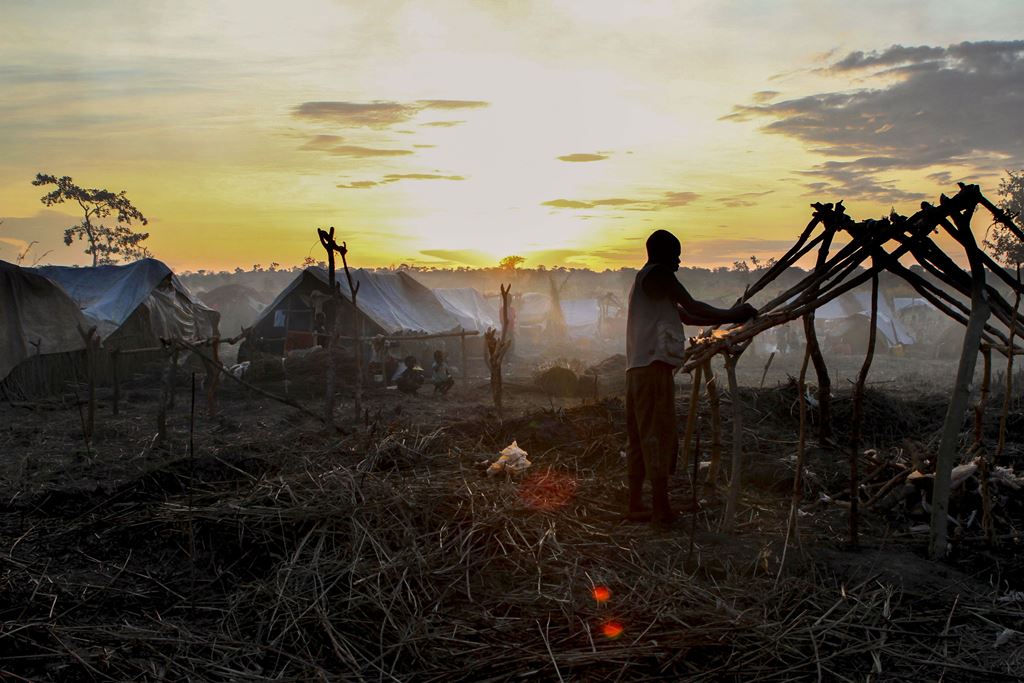 (FILES) This file photo taken on October 19, 2016 shows a man building a tent at sunset in the newly formed camp for internally displaced people in Kaga Bandoro. AFP / EDOUARD DROPSY