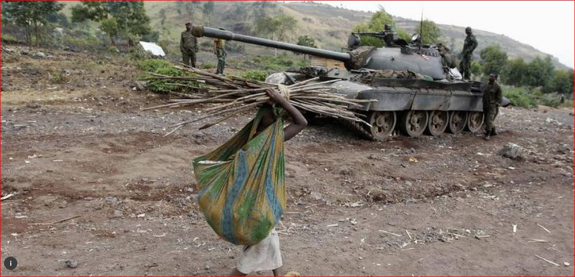 In a 2013 file photo, a girl carries firewood as she walks past a Congolese government military tank in Kanyarucinya, near Goma in the eastern Democratic Republic of Congo. REUTERS/Thomas Mukoya