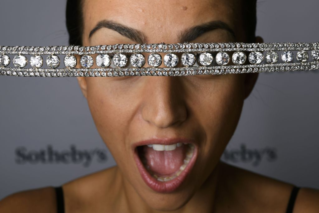 A model poses with a diamond necklace with a stunning and delicate bowknot clasp during a press preview by Sotheby's auction house on November 9, 2016 in Geneva.  AFP / FABRICE COFFRINI