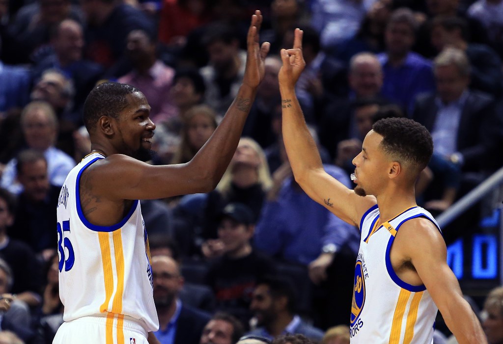 Kevin Durant #35 and Steph Curry #30 of the Golden State Warriors high five during the first half of an NBA game against the Toronto Raptors at Air Canada Centre on November 16, 2016 in Toronto, Canada. Vaughn Ridley/Getty Images/AFP