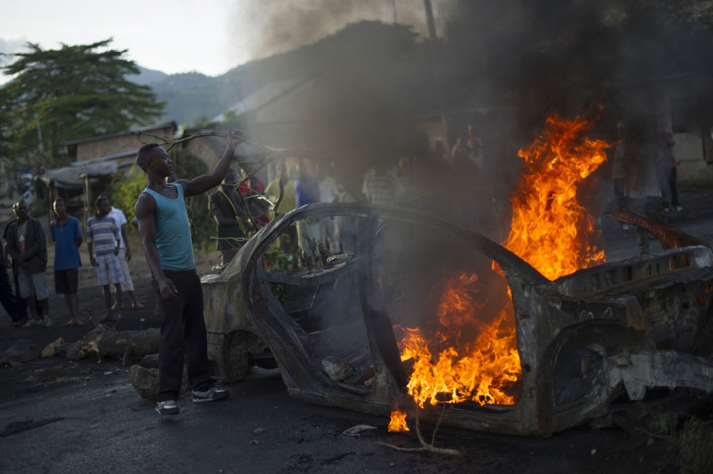 A protestor fuels a burning barricade in the Musaga neighbourhood of Bujumbura, Burundi. 
