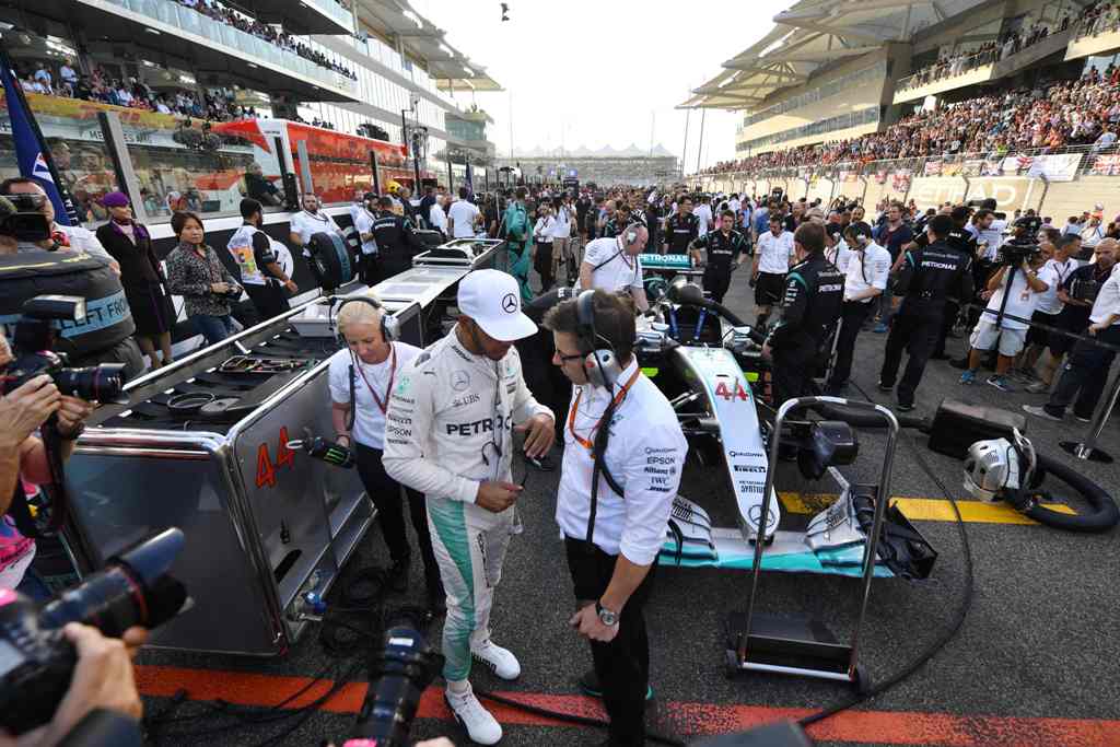 Mercedes AMG Petronas F1 Team's British driver Lewis Hamilton (C-L) talks to a member of his team ahead of the start of the Abu Dhabi Formula One Grand Prix at the Yas Marina circuit on November 27, 2016. / AFP / Andrej ISAKOVIC
