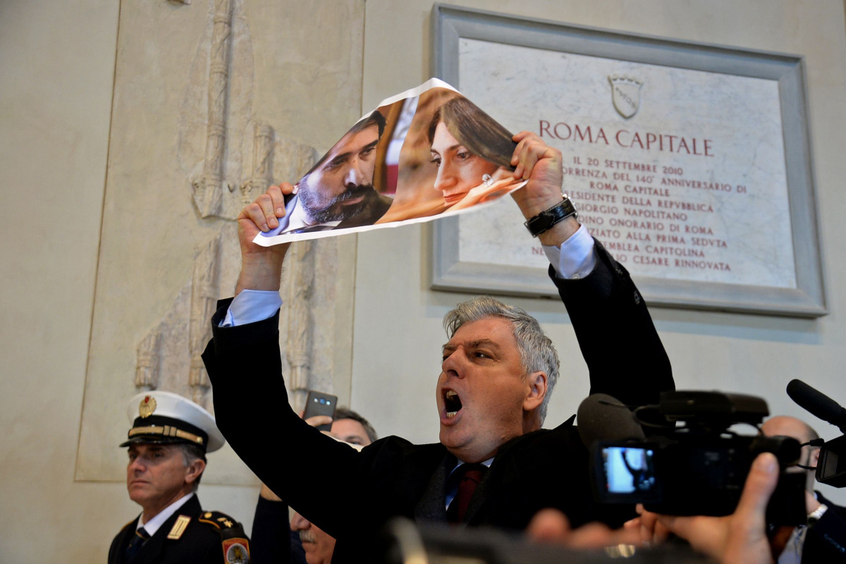 An opposition city councillor holds a placard picturing Rome's mayor Virginia Raggi and her head of personnel Raffaele Marra, as he protests during the town council assembly at the Campidoglio, in Rome, on December 16, 2016. Rome's mayor Virginia Raggi, t