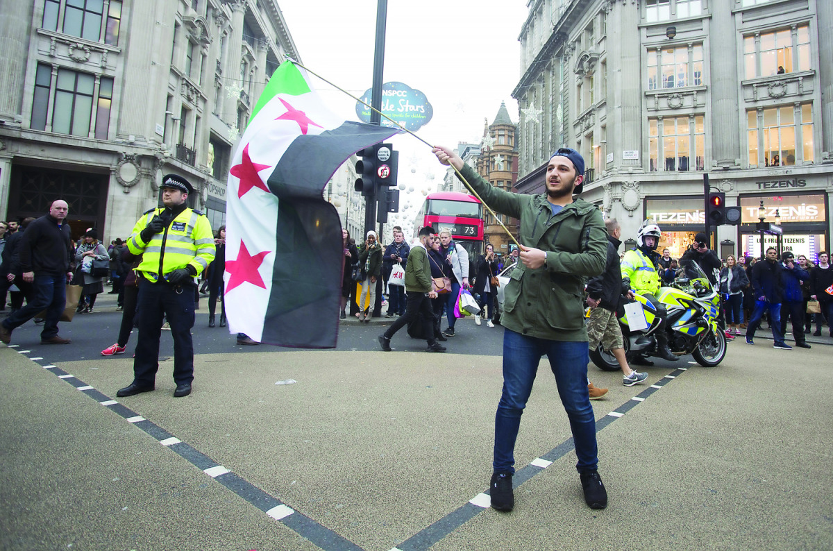 People gather to demonstrate condemning massacres and attacks in Syria's Aleppo over civilians in a march from Marble Arch to Downing Street in London, yesterday.