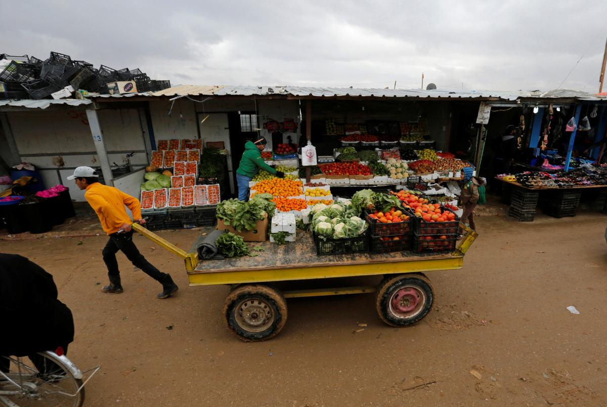 A Syrian refugee transports a vegetable cart during rainy weather at the Al Zaatari refugee camp in the Jordanian city of Mafraq, near the border with Syria December 18, 2016. REUTERS/Muhammad Hamed