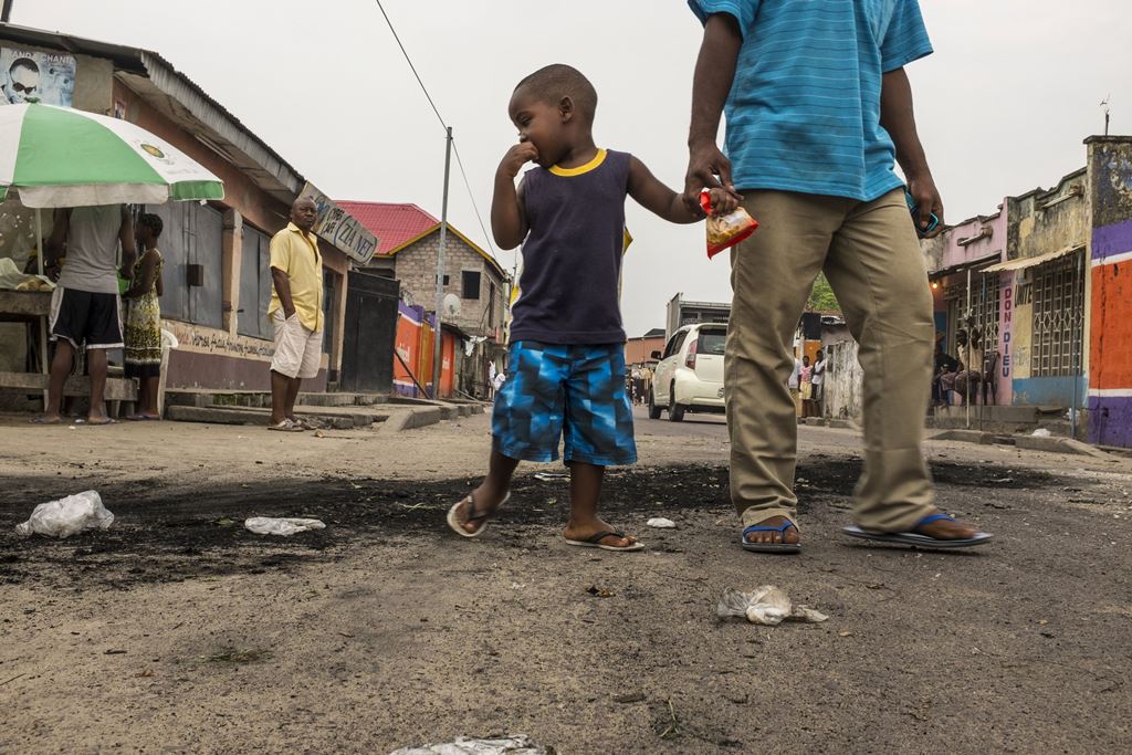 (FILES) This file photo taken on December 20, 2016 shows a child staring at the marks of burnt tyres following a protest in the Lingwala neighborhood in Kinshasa. AFP / Eduardo Soteras
