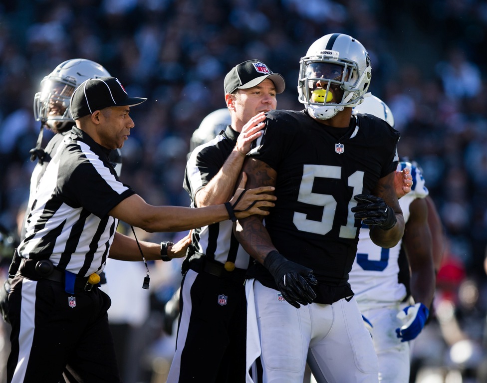 Referees hold back Oakland Raiders outside linebacker Bruce Irvin (51) after a play against the Indianapolis Colts during the second quarter at the Oakland Coliseum. Kelley L Cox