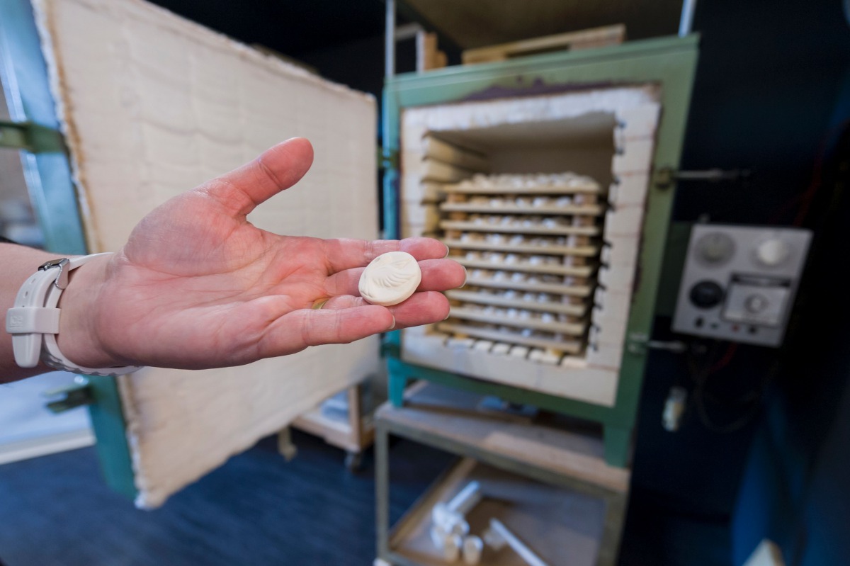 This file photo taken on November 3, 2016 shows a person holding a charm for king cakes traditionally eaten on Twelfth Night, the eve of Epiphany, during the production process, in Autreville, eastern France. In their small workshop in eastern France, sis