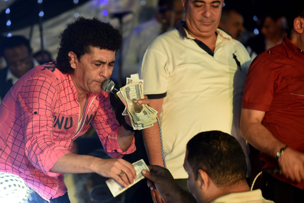 Egyptian master of ceremonies collects money at a wedding in the Egyptian Qalyubia governorate, north of Cairo on October 14, 2016. Under a large colourful tent set up in farmland, lit up with bright white bulbs, about 500 attendees sit in a fog of smoke 