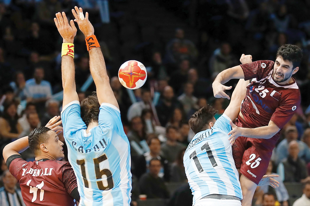 Qatar's centre back Kamal Mallash (right) jumps to shoot at the goal over Argentina's pivot Lucas Moscariello (second right) and pivot Gonzalo Carou during their 25th IHF Men's World Championship 2017 Group D handball match played at the AccorHotels Arena