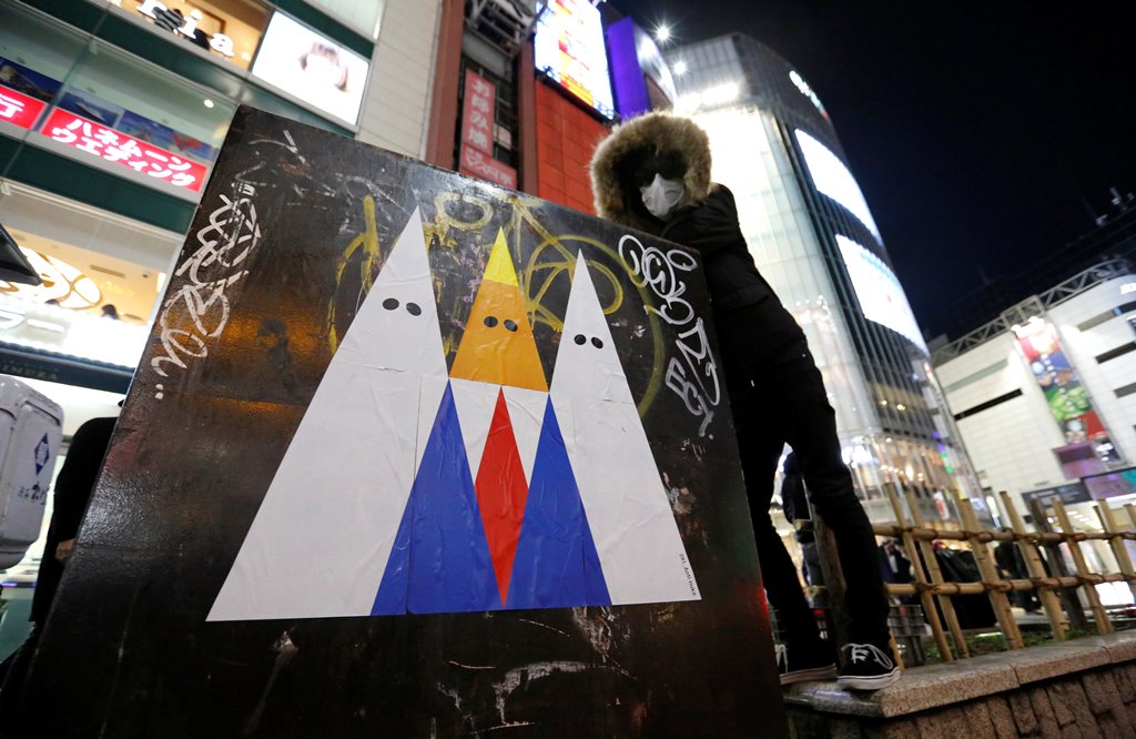 A Japanese graffiti artist known as 281 Antinuke poses for a photo with his sticker art depicting U.S. President Donald Trump in Tokyo's Shibuya shopping and entertainment district, Japan, January 27, 2017. Reuters/Toru Hanai 