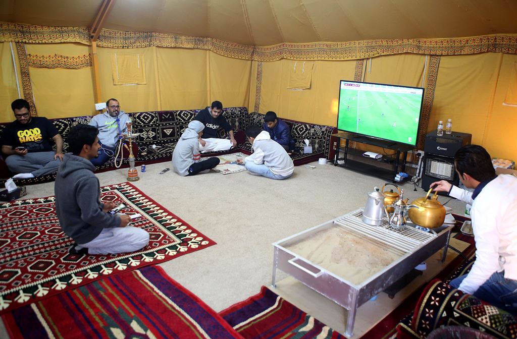 Men watch TV, play games and drink tea while gathering at a tent in a winter camp close to the border with Saudi Arabia, in al-Julaia, around 70 kilometres (45 miles) from the capital Kuwait City. AFP / Yasser Al-Zayyat