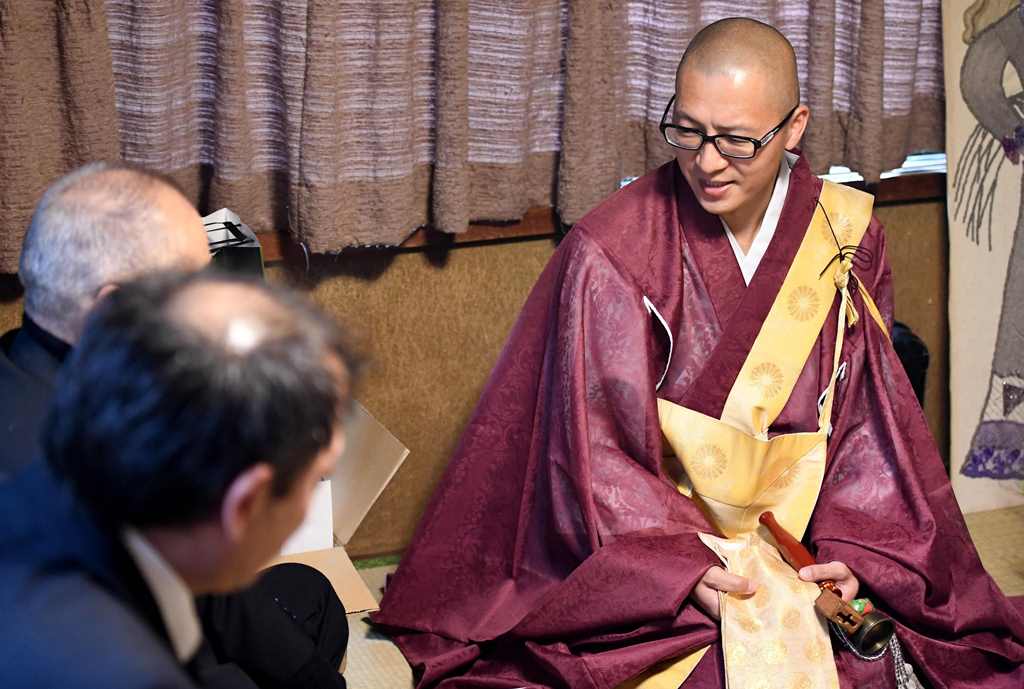 This picture taken on November 10, 2016 shows Buddhist monk Kaichi Watanabe (R) speaking to relatives during the one-year anniversary of a woman's death at her home in Funabashi, Chiba prefecture, a suburb of Tokyo. AFP / Toshifumi KITAMURA 