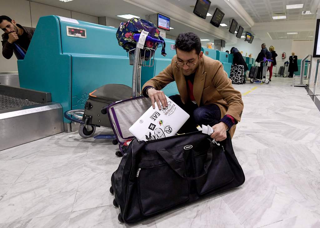 A Libyan traveller packs his laptop in his suitcase before boarding his flight for London at Tunis-Carthage International Airport on March 25, 2017. / AFP / FETHI BELAID
