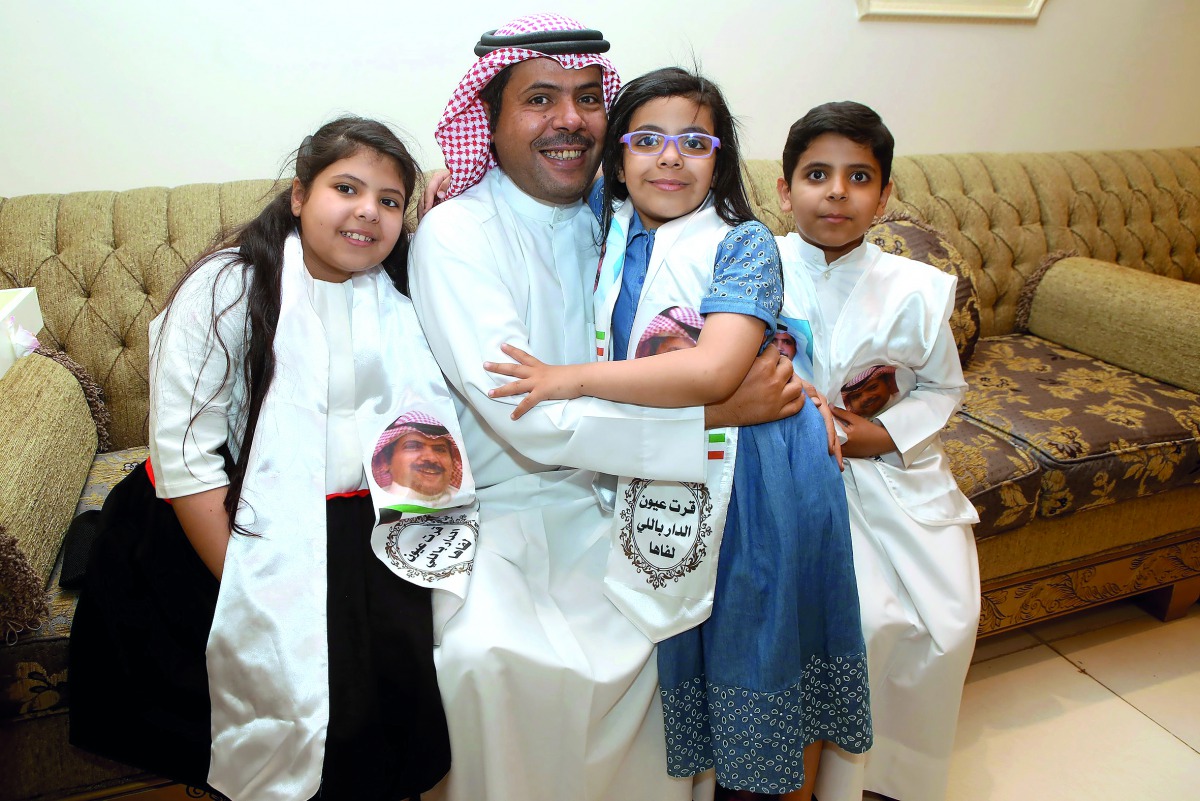 Saad al-Ajmi (C), former spokesman of the opposition Popular Action Movement, hugs his children upon his return home on March 30, 2017, south of Kuwait City. Ajmi, who was deported to Saudi Arabia after revoking his citizenship was allowed to return home 