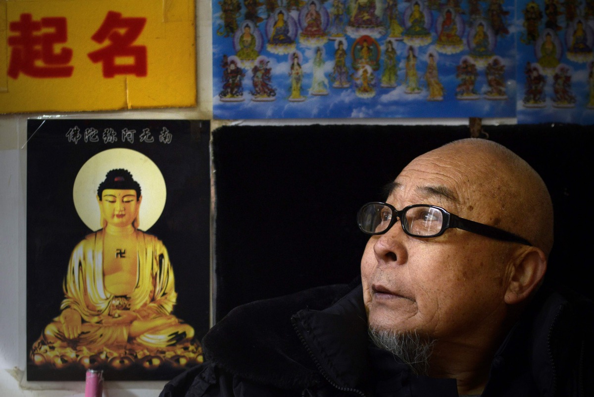 This picture taken on February 28, 2017 shows fortune-teller Mao Shandong looking on as he waits for customers in his shop in Beijing. In a one-room shop tucked inside a Beijing alley, a bearded 74-year-old fortune-teller in crimson tunic offers what Chin