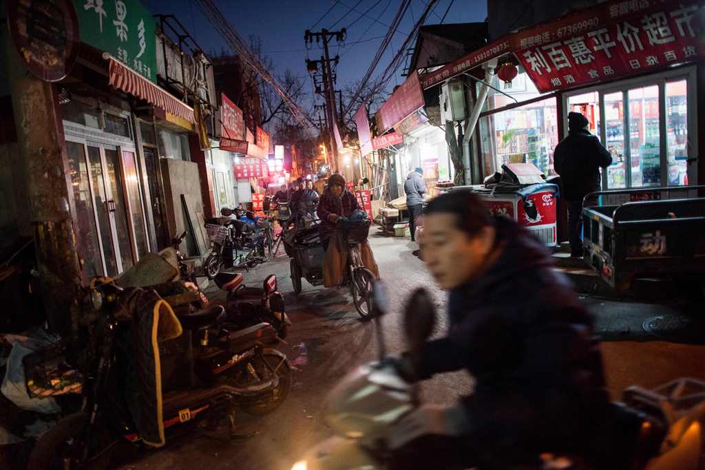 This picture taken on December 5, 2016 shows people riding in a hutong in Beijing. AFP / Fred DUFOUR