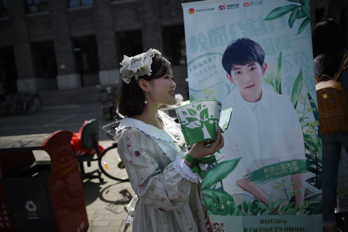 A woman handing out leaflets during an event for fans of China's boy band sensation TFBoys 