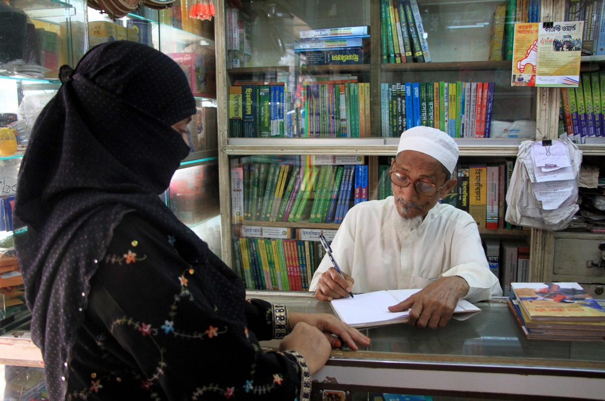 In this photograph taken on April 17, 2017, Bangladeshi novelist Kasem bin Abubakar signs an autograph for a relative at his book shop in Dhaka. AFP