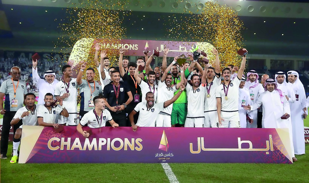 Al Sadd players and officials celebrate with the Qatar Cup Trophy. 