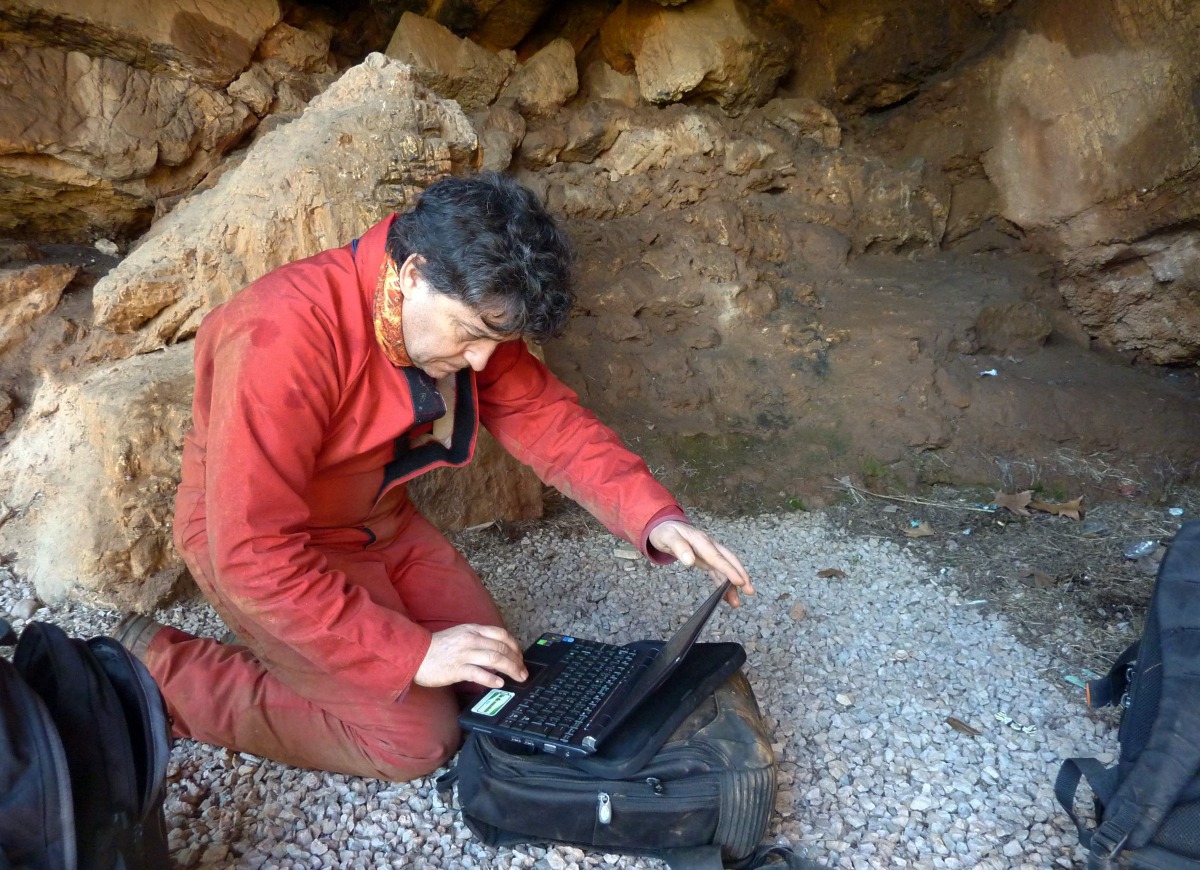 Archeologist Hipolito Collado checks his laptop prior to entering the Maltravieso Cave in the outskirts of Caceres, on February 17, 2017. AFP Photo / Handpas Project