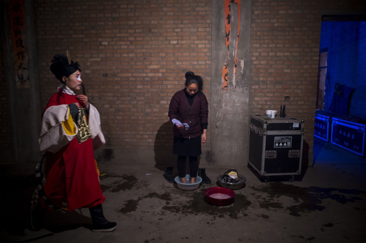 This picture taken on March 30, 2017 shows a Jin opera performer (C) having a footbath backstage after a show at an outdoor theatre in a village in Yuxian, China's Hebei province. AFP / Wang Zhao