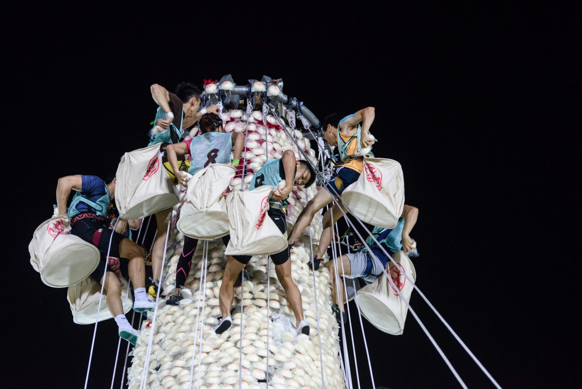 Competitors take part in a scramble up an 18-metre tower made from imitation buns during the annual Cheung Chau bun festival in Hong Kong, shortly after midnight on May 4, 2017. AFP / Anthony Wallace