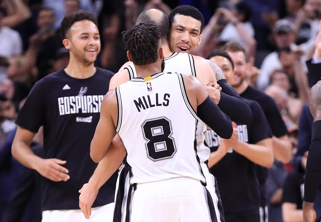 Danny Green #14 hugs Manu Ginobili #20 and Patty Mills #8 of the San Antonio Spurs after an overtime win against the Houston Rockets during Game Five of the Western Conference Semi-Finals at AT&T Center on May 9, 2017 in San Antonio, Texas.  Ronald Martin