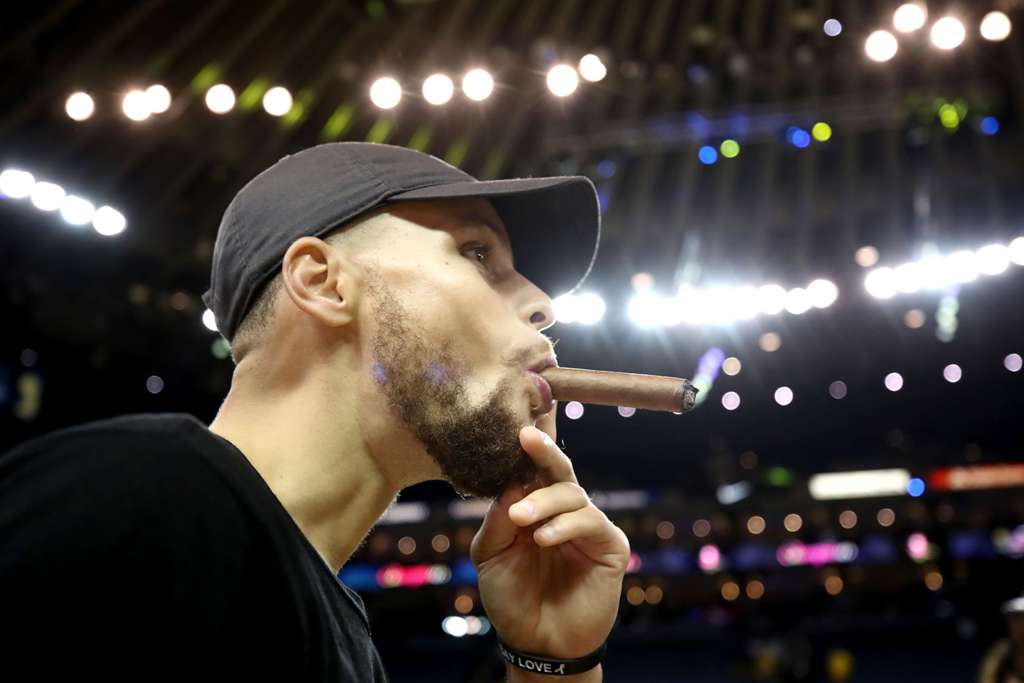 Stephen Curry #30 of the Golden State Warriors smokes a cigar after defeating the Cleveland Cavaliers 129-120 in Game 5 to win the 2017 NBA Finals at ORACLE Arena on June 12, 2017 in Oakland, California.  Ezra Shaw/AFP