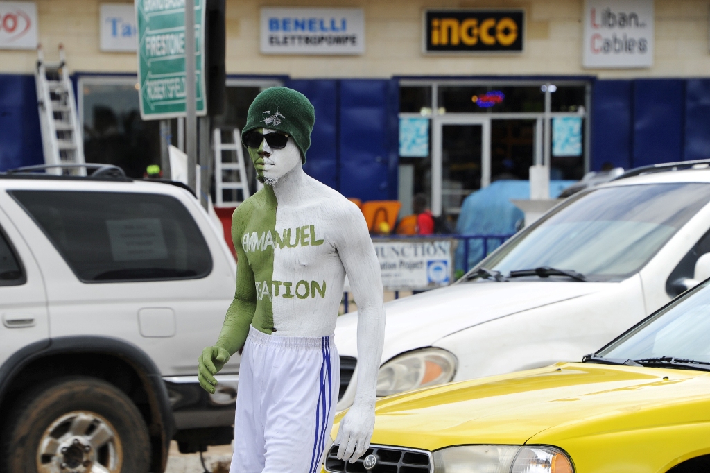 A man stands in the sweltering heat for hours, painted head to toe in the colours of a fashion house, at a traffic junctions in the Liberian capital of Monrovia on May 25, 2017. AFP / Zoom DOSSO
