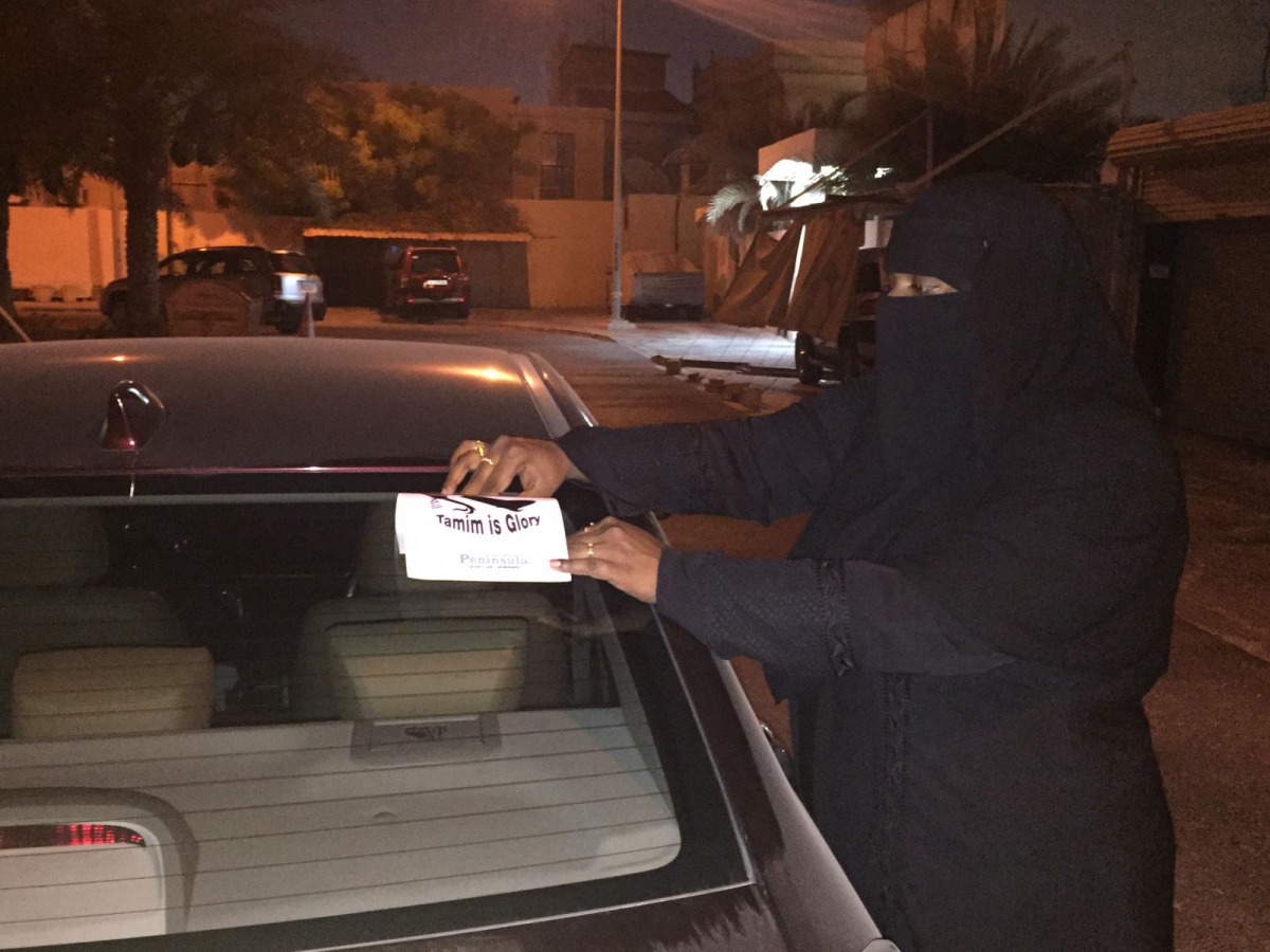 An expat women paste a sticker supplied by The Peninsula on a car. Pic: Fazeena Saleem