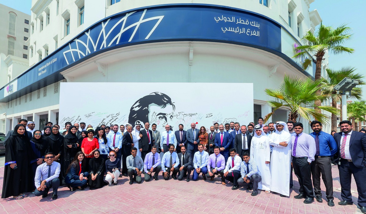 IBQ staff in front of the ‘Tamim Al Majd’ mural at its main branch. 
