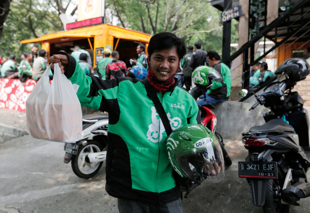 A Go-Jek driver shows boxes with food for his customer in front of a food stall in Jakarta, Indonesia, July 13, 2017. Reuters/Beawiharta