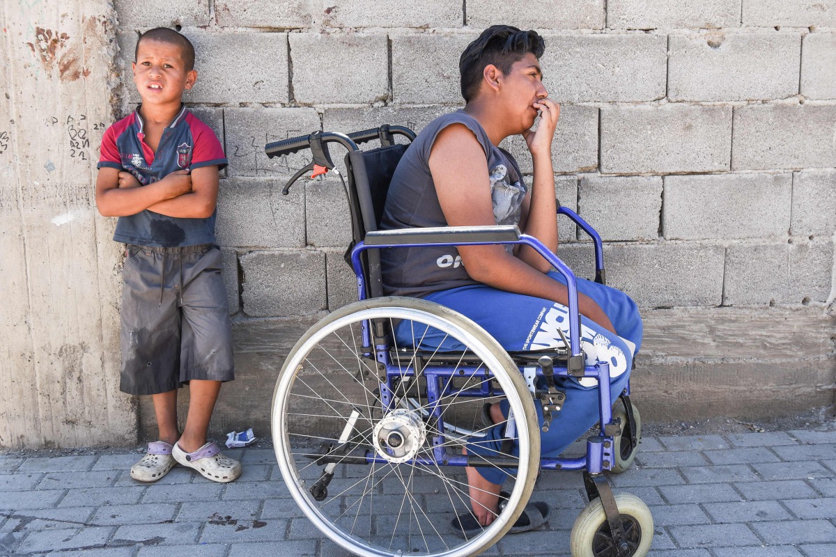 Jetullah Veliu, 16-years-old, sitting on a wheelchair along a street in the Roma neighborhood in the town of Mitrovica on July 7, 2017. AFP / Armend Nimani