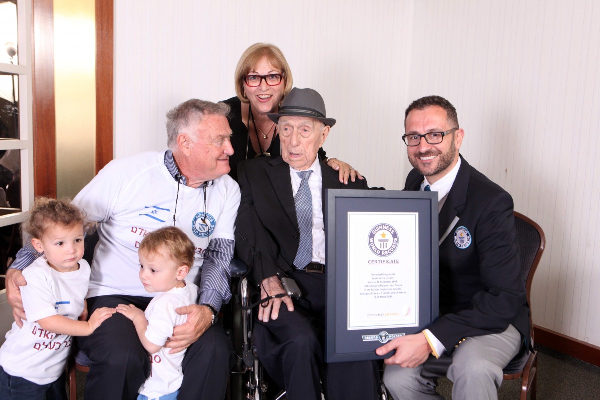 Marco Frigatti (R), Head of Records for Guinness World Records, presenting Israel Kristal (2nd-R) with his certificate of achievement for Oldest Living man, in the presence of the Kristal's daughter (top, son (L) and grandchildren In this picture released