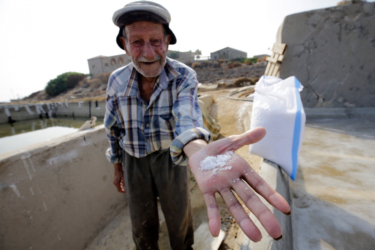 Elias al-Najar, 93, displays salt flakes in the coastal Lebanese town of Anfeh north of the capital Beirut on July 21, 2017.  AFP / Ibrahim Chalhoub