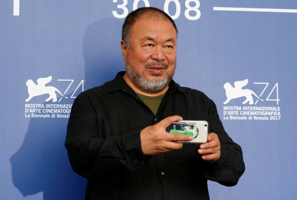 Director Ai Weiwei takes a picture as he poses during a photocall for the movie 