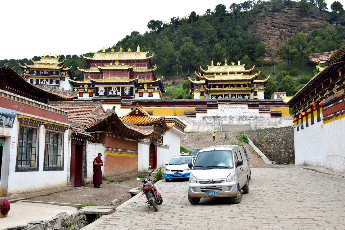 A monk pauses to look at a taxi arriving for pickup at Sertri Monastery, one of two in Langmusi, a small town that straddles China's Sichuan and Gansu provinces. (Photos by William Ford for The Washington Post)