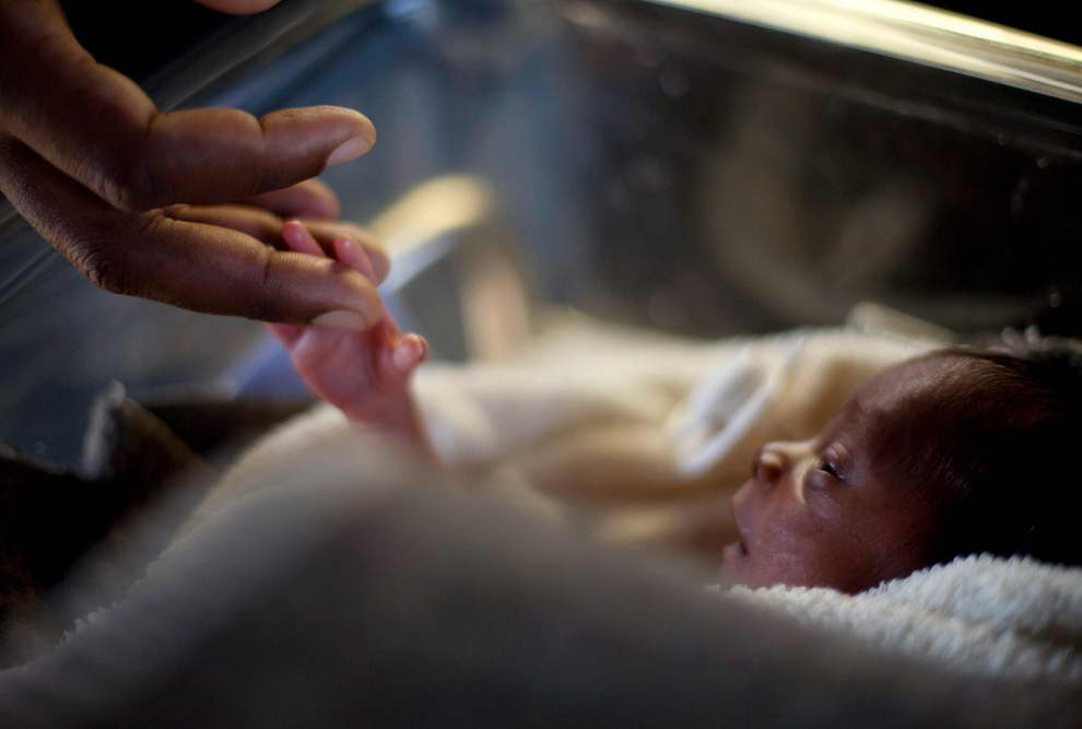 FILE PHOTO: A man touches his newborn baby born three days earlier at the Israeli hospital in Port-au-Prince, January 20, 2010.  Reuters / Carlos Garcia Rawlins