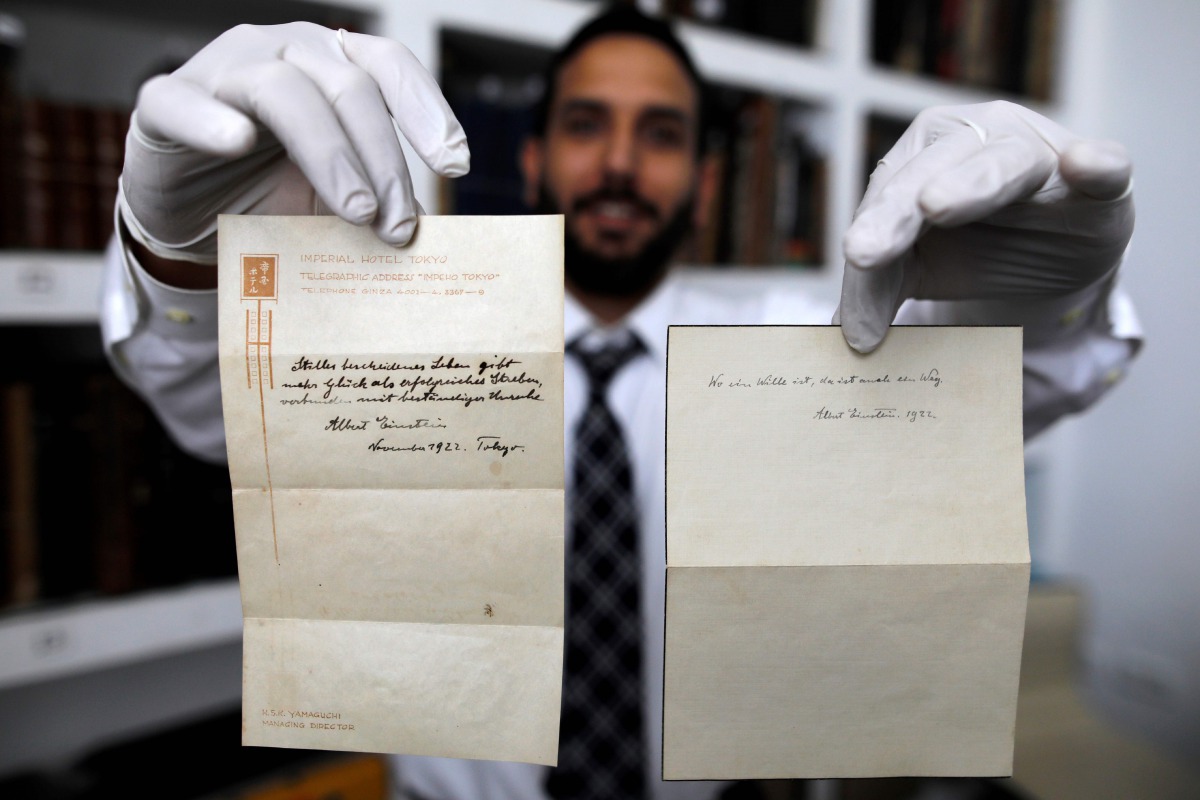 A picture taken on October 19, 2017, shows Gal Winner, owner and manager of the Winner's auction house in Jerusalem, displays one of two notes written by Albert Einstein, in 1922, on hotel stationary from the Imperial Hotel in Tokyo Japan. AFP / Menahem K