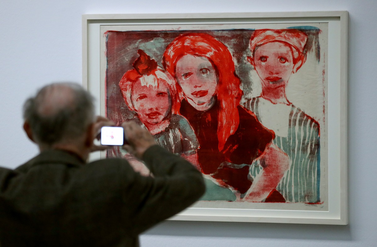 A man takes a picture of the lithograph 