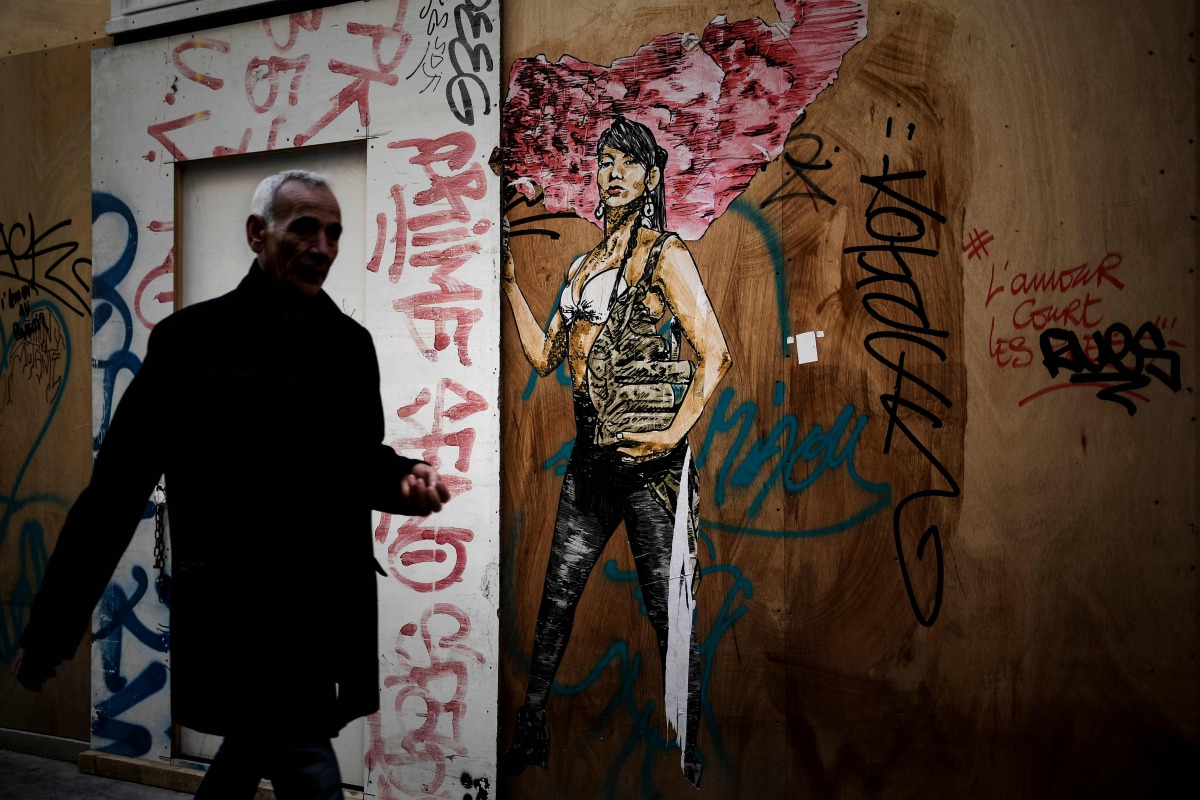 A man walks past a graffiti in a street of Paris on November 7, 2017. AFP / Philippe Lopez

