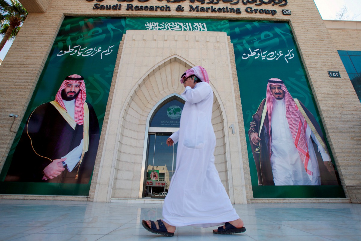 A man speaks on the phone as he walks past posters depicting Saudi Arabia's King Salman bin Abdulaziz Al Saud and Crown Prince Mohammed bin Salman in Riyadh, Saudi Arabia, November 9, 2017. Reuters/Faisal Al Nasser 