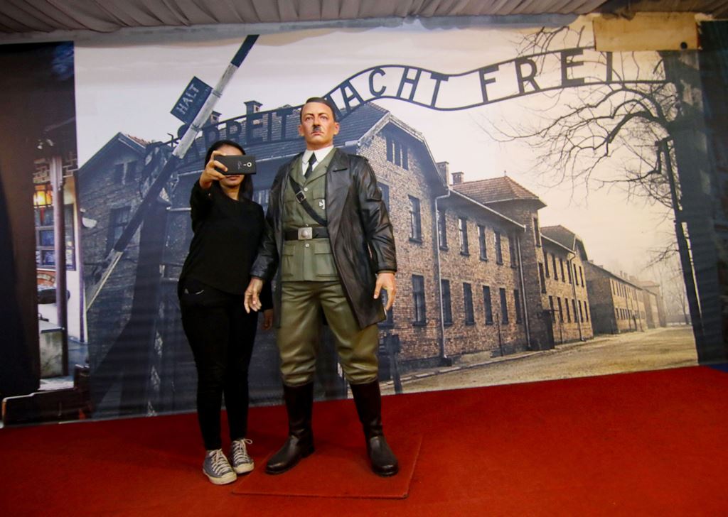 This photograph taken on November 10, 2017 shows an Indonesian woman take a selfie with a life-size wax sculpture of Adolf Hitler at a museum in Yogyakarta. AFP / HENRYANTO