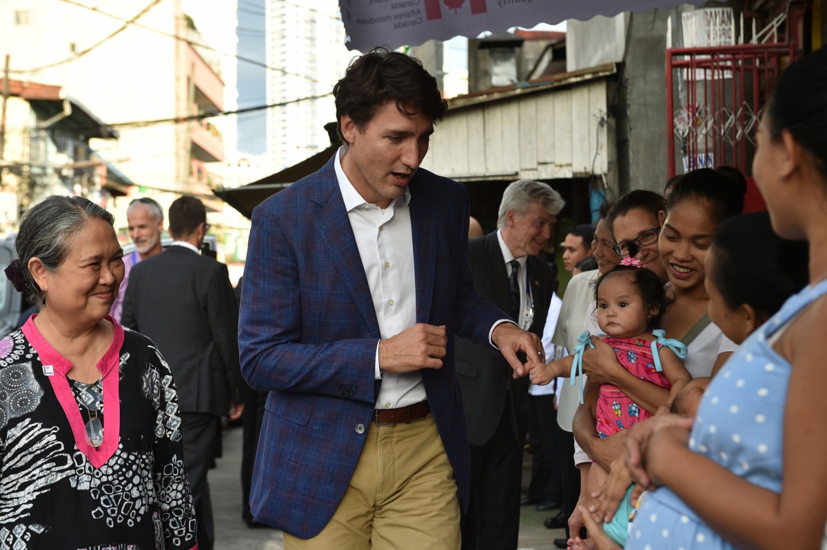 This photo taken on November 12, 2017 shows Canada's Prime Minister Justin Trudeau (C) greeting mothers at a clinic run by the non-governmental organisation Likhaan during a visit on the sidelines of the Association of Southeast Asian Nations (ASEAN) summ