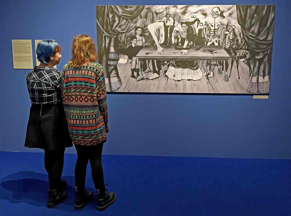 Visitors look at a black-and-white reproduction of a painting titled 