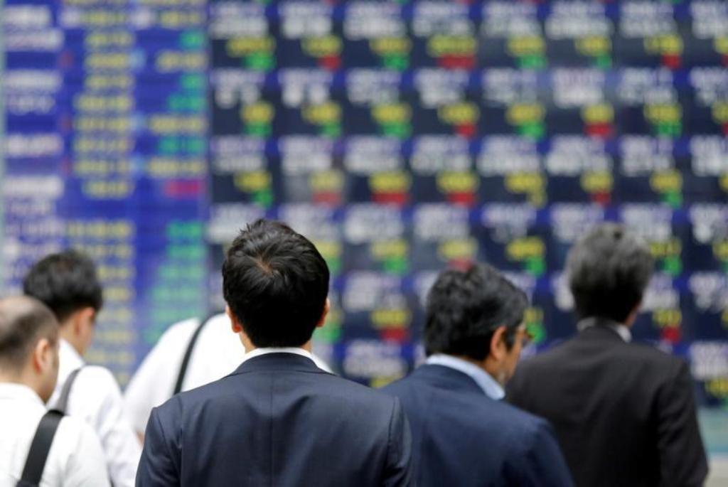 FILE PHOTO: People walk past an electronic stock quotation board outside a brokerage in Tokyo, Japan, September 22, 2017. REUTERS/Toru Hanai/File Photo.